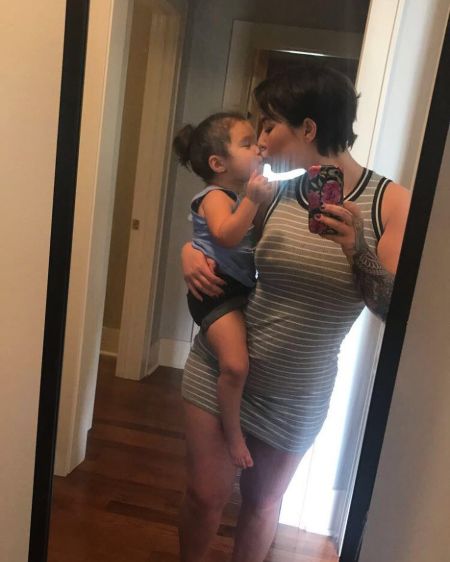 Molly Noriko Hurley lovingly kisses her baby Kimiko Flynn in this mirror selfie while carrying her at the waist sideways.